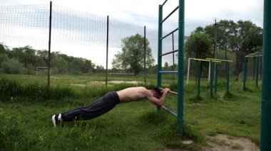 Spor malzemelerinde trisepsler üzerinde egzersiz yapan genç kaslı bir atlet. Spor alanında spor yapan erkek üstsüz bir sporcu. Doğada güçlü bir sporcu eğitimi. Sağlıklı yaşam tarzı kavramı.