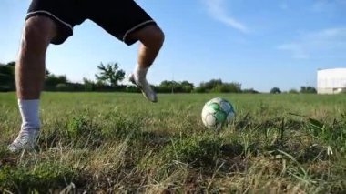 Profesyonel futbolcunun erkek ayağı, yeşil sahada koşarken topla numaralar gösterir. Güneşli bir günde Meadow 'da koşan sporcu bacakları topa vurur. Stadyumda antrenman yapan genç adam. Yavaş çekim