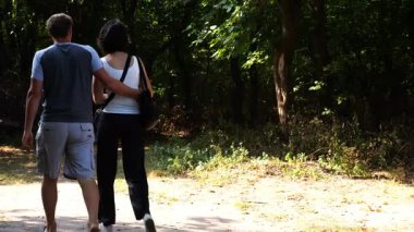 Mutlu çift yaz ormanında yolda yürüyor. Vahşi ormanlık alanda romantik bir çift geziyor. Sevgililer doğada birlikte vakit geçirirler. Aşk ve mutluluk kavramı. Yavaş çekim