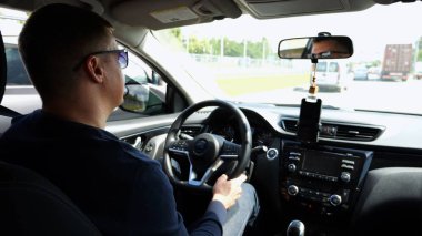 Güneş gözlüklü kendine güvenen adam otomobil sürerken kentsel yola odaklanmış görünüyor. Kasabada araba kullanan ciddi bir erkek sürücü. Otoyolda çalışan bir adam. Yavaş çekim