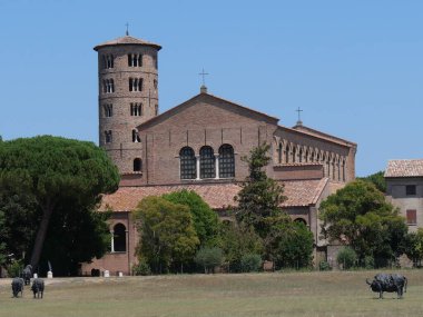 Sant 'Apollinare in Classe Bazilica in Ravenna, the brick front with the circular bell tower in Bizans style and the green lawn in front.