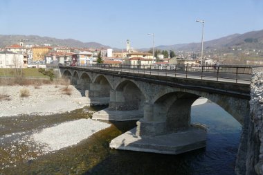 Borgotaro köyünün panoraması Taro nehri üzerinde kemerli köprü ve arka planda tepeler.