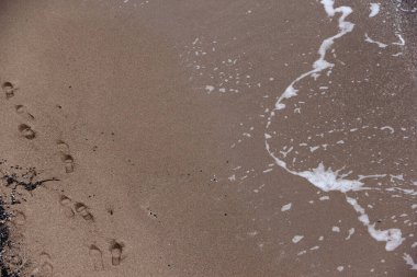 Deniz kıyısındaki kumda insan ayak izleri var.