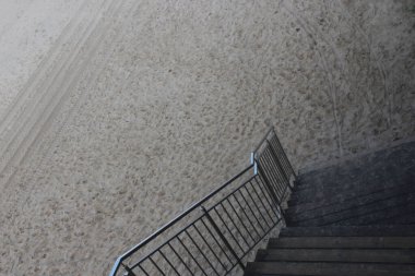 Metal tırabzanlı bir merdiven kumlu sahile çıkıyor.