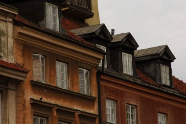 Kapalı cepheli tarihi yerleşim yerleri, yurt pencereleri, kırmızı fayanslı çatılar, sıcak kahverengi ve turuncu renklerde eskimiş dokular, klasik bir atmosfer için bulutlu ışıkta yakalanmış.