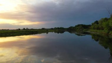 İHA görüntüleri gölgeli araziden yükselen güneşe kadar yayılıyor. Pürüzsüz kamera hareketi nehir yansımasını, yalnız ağaç siluetini ve renkli sabah gökyüzünü gözler önüne serer..