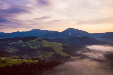 Gün doğumunda vadide sis ve dağınık köy evleri ile hava manzaralı Karpat Dağları