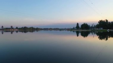 Gün doğumunda sakin nehrin, ağaçların ve durgun sulardaki gökyüzünün ayna yansımalarıyla çekilmiş hava aracı videosu. Arka plan, seyahat, turizm ve rahatlama görüntüleri için mükemmel..