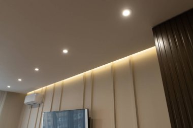 Bir apartman dairesinde parlak ışıklandırma ve zarif duvar dokusu içeren modern iç tasarım.