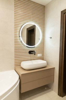 Modern banyo tasarımı gösterişli, minimalist bir ayna ve sıcak ahşap aksanlı kentsel bir dairede huzurlu bir atmosfer yaratıyor.