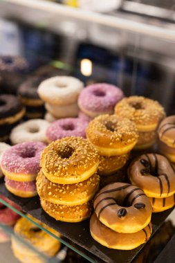 Yerel bir pastanede cazip bir şekilde istiflenmiş renkli çöreklerin leziz çeşitleri, güneş ışığında eşsiz tatlar ve malzemeler sergiliyor.