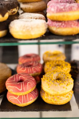 Renkli bir pastane vitrininde her lokmada hoşgörü gösteren çeşitli donutlar.