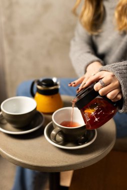 Rahat bir kafede sakin bir öğleden sonra toplanırken zarif fincanlara güzel kokulu bitki çayı dökülüyor.
