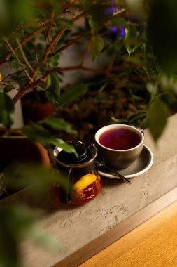 Huzurlu bir kafede rahat bir köşe. Bir fincan narin bitki çayı ve yemyeşil bir yerde bir kavanoz bal.