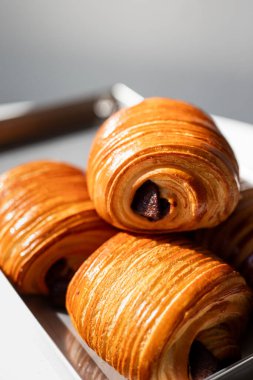 Modern bir kafe ortamında doğal ışığı olan minimalist gri bir tabakta servis edilen tatlı.