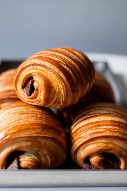 Sıcak bir pastanede gümüş tepside taze pişmiş çikolatalı kruvasanlar.