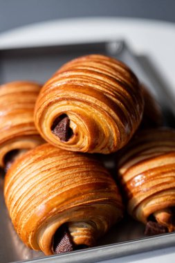 Tepside taze pişmiş çikolatalı kruvasanlar, altın-kahverengi katmanlar sergileniyor ve cazip dolgular, kahvaltı için mükemmel ya da atıştırmalık
