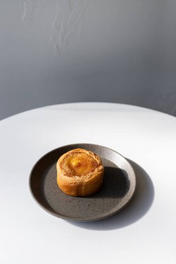 Modern bir kafe ortamında doğal ışığı olan minimalist gri bir tabakta servis edilen tatlı.