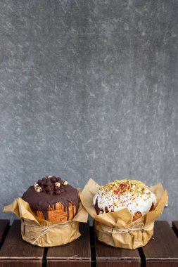 Nefis dekore edilmiş pastalar, ahşap masa üzerindeki çikolata ve krema malzemeleriyle desenli arka planda.