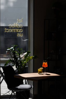 Parlak ışıklı bir kafe köşesi ve öğleden sonra bir saksı bitkisinin yanındaki masada içkiler