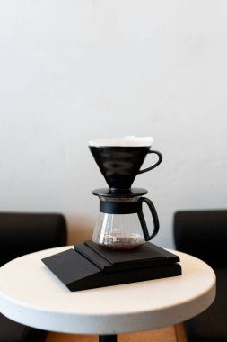 Modern bir kafe ortamında, basit bir masanın üzerine dökülen damlatıcıyla kahve yapmak.