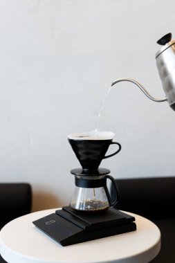 Sıcak aydınlatma ve minimalist tasarımı olan rahat bir kafede damlatma metodu kullanarak kahve yapmak.