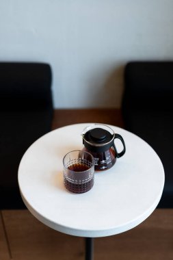 Modern bir kahve sehpası minimalist bir masada, şık bir dinlenme odasında bir bardak ve sürahi ile.