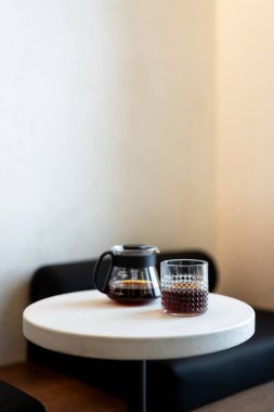 Kahve demliği ve bir bardak demlenmiş kahve öğleden sonra sıcacık bir kafede yuvarlak bir masada.