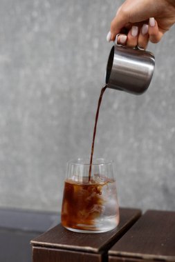 Öğleden sonra modern bir ortamda bir kafede buzla dolu bir bardağa soğuk kahve doldurmak.