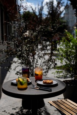 Öğleden sonra güneşli bir sokakta içkiler ve hamur işleriyle dolu açık hava yemekleri.