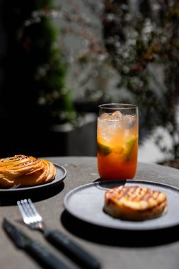 Delicious pastries served with a refreshing drink on a sunlit outdoor table in a cozy caf setting during a warm afternoon clipart