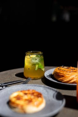 Öğleden sonra güneşli bir kafede taze pişmiş hamur işlerinin yanında ferahlatıcı bir içkinin tadını çıkarıyorum.