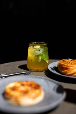 Sıcak bir öğleden sonra, karanlık bir masadaki hamur işlerinin yanında içecekleri tazeliyorum.