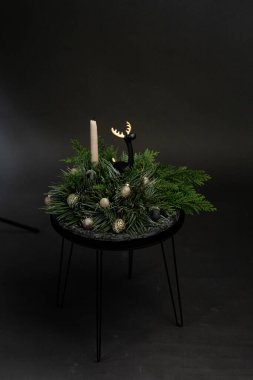 Minimalist bir masada mum ve yeşillik içeren zarif bir kış süsü.