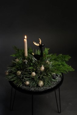Bir mum, ebedi yeşil dallar ve dekoratif süsler içeren rahat bir kış süsü, tatil sezonu boyunca şenlikli toplantılar için mükemmel.