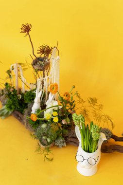 A whimsical garden arrangement featuring unique sculptures and vibrant flowers against a bright yellow backdrop during springtime clipart