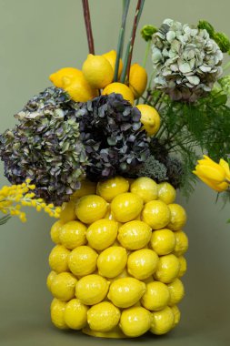 Canlı bir dekor için modern düzende yaratıcılığını gösteren taze çiçeklerle süslenmiş canlı bir limon süsü.