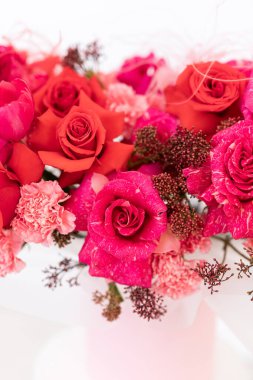 Yumuşak ışıkta yakalanan hassas aksanlar arasında kırmızı ve pembe güller.