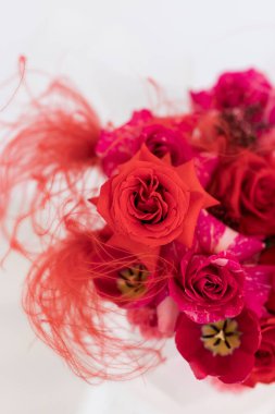 Zarif bir kutlama için canlı bir buket kırmızı gül ve zarif, tüylü aksanlarla süslenmiş renkli çiçekler.