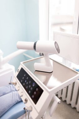 Parlak, iyi ışıklandırılmış bir tedavi odasında rutin bir muayene sırasında profesyonel bir diş hekiminde modern diş aletleri.