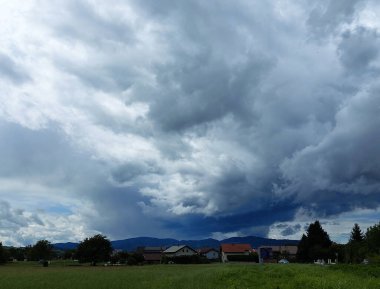 Evlerin üzerinde koyu gri bulutlar. Slovenya. Fırtınadan önce gök