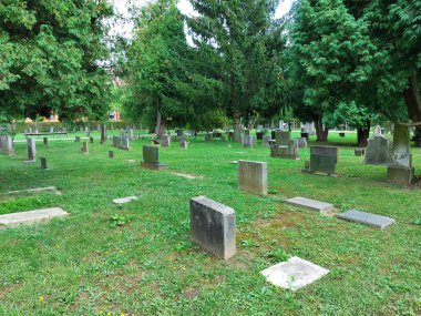 Yeşil çimlerin üzerinde eski mezar taşları. Ptuj 'daki Katolik mezarlığı. Slovenya