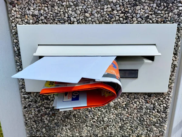 close-up - white mailbox with letters and advertising catalogs