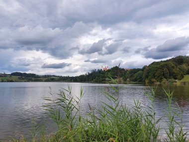 Yeşil tepelerdeki kutsal üçleme gölü ve kilisesi. Bulutlu. Slovenya