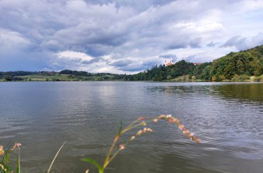 Kara Göl ve Kutsal Üçlü Kilisesi (Sveta Trojica) yeşil tepelerde. Bulutlu. Slovenya