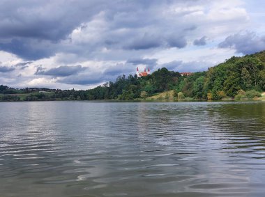 Slovenske Gorice 'deki Kutsal Üçleme Kilisesi' nin yanındaki gölün karanlık suları bulutlu gökyüzünün altında. Slovenya