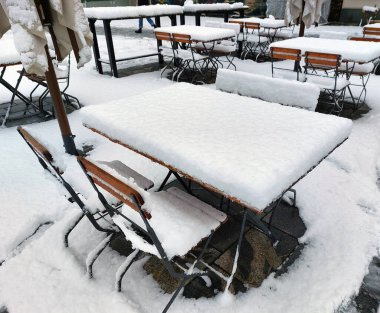 Masalarda ve sandalyelerde taze kar. Kafenin terası. Maribor, Slovenya. Kış mevsimi