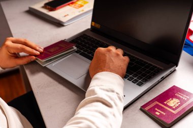 Ofiste çalışıyor, pasaportlarla oynuyor. Bilgisayar, klavye, fare