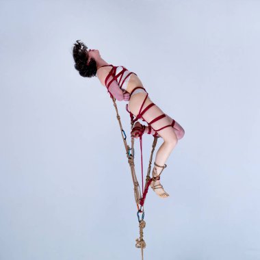 Beyaz dantelli iç çamaşırlı güzel bir kız Shibari ipleriyle bağlanmış.