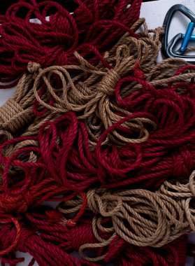 Shibari için bir sürü kırmızı ve kahverengi ip ve bağlayıcı.